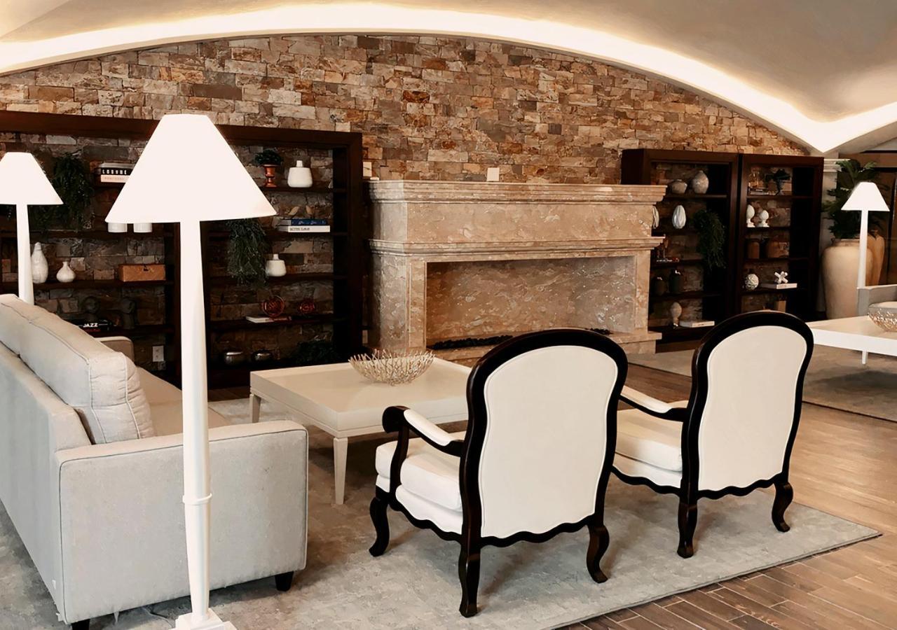 Buona Vitta Gramado Resort & Spa By Gramado Parks מראה חיצוני תמונה The photo shows a stylish living room with a modern design. In the center, there is a light-colored sofa and two elegant white armchairs with black wooden frames. A coffee table is placed in front of the sofa. Behind them, there is a large, decorativ
