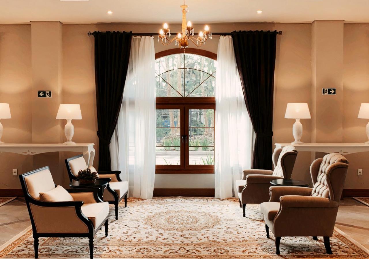 Buona Vitta Gramado Resort & Spa By Gramado Parks מראה חיצוני תמונה The photo shows an elegantly styled living room. There are two armchairs and a sofa arranged comfortably around an intricate area rug. Large windows are adorned with sheer white curtains and dark curtains, allowing natural light to fill the space. A 