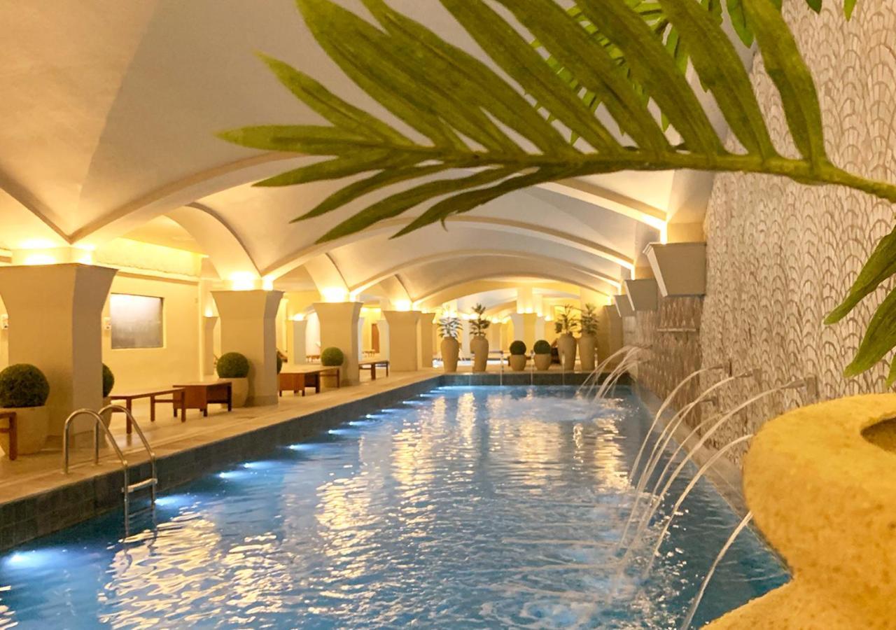 Buona Vitta Gramado Resort & Spa By Gramado Parks מראה חיצוני תמונה The photo shows an indoor swimming pool with a serene and elegant atmosphere. The pool has a calm blue water surface, illuminated by soft lights along its edges. The architectural design features arches in the ceiling, creating an open and spacious f