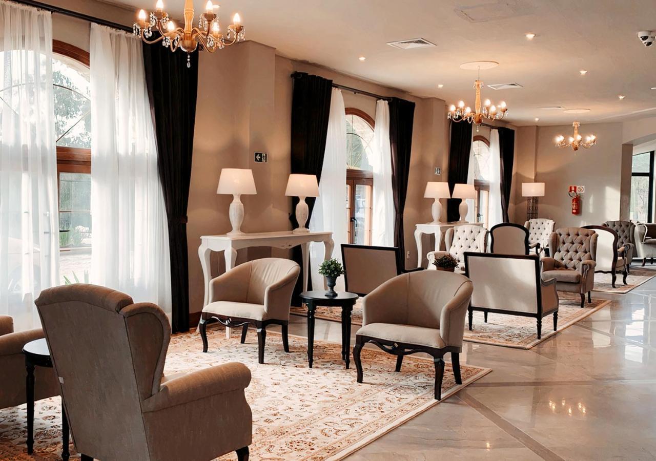 Buona Vitta Gramado Resort & Spa By Gramado Parks מראה חיצוני תמונה The photo depicts a stylish and sophisticated lounge area. It features several elegant chairs and sofas, arranged around small tables on a decorative rug. The room is well-lit with natural light coming in through large windows dressed with flowing wh
