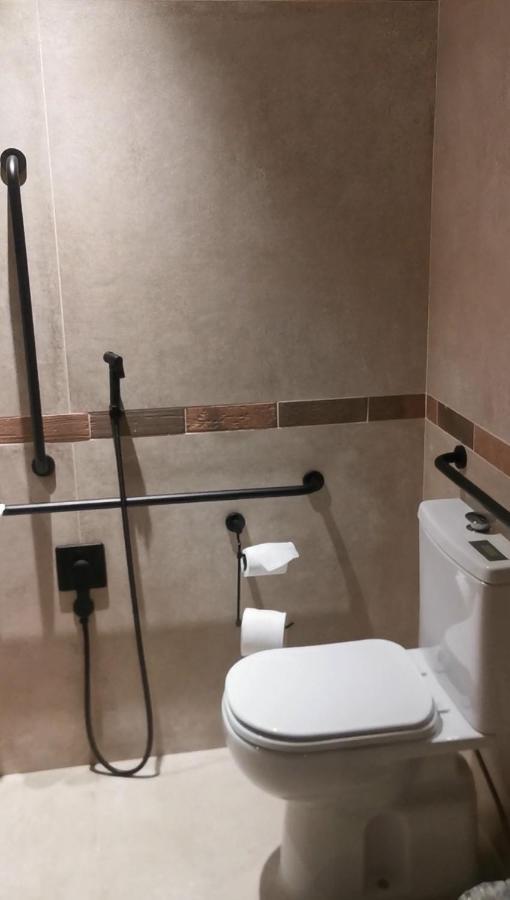 Buona Vitta Gramado Resort & Spa By Gramado Parks מראה חיצוני תמונה The photo shows a bathroom equipped with grab bars for accessibility. The walls are tiled in a neutral color, and there is a toilet on the right side of the image. Two rolls of toilet paper are positioned near the toilet, and there are additional ins