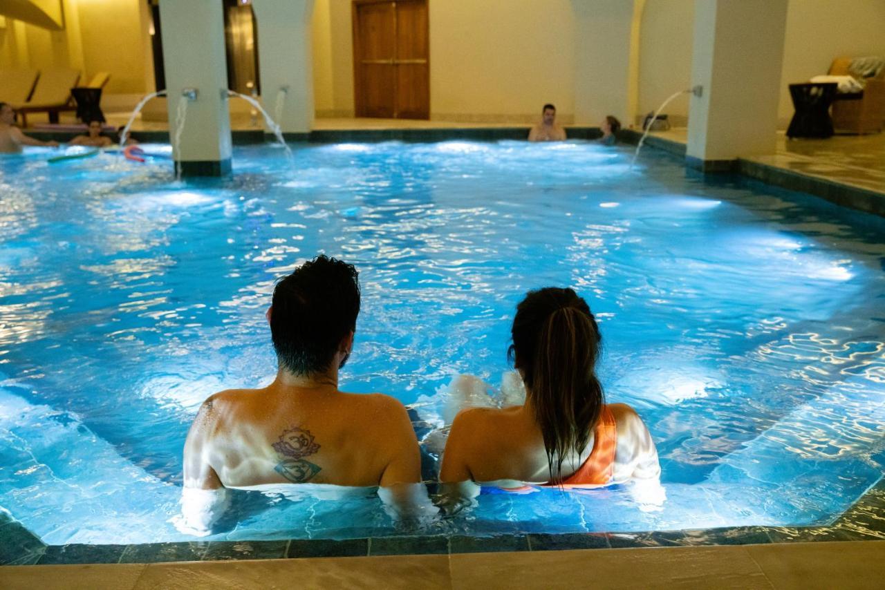Buona Vitta Gramado Resort & Spa By Gramado Parks מראה חיצוני תמונה The photo shows a couple sitting in a swimming pool with gentle lighting. They are facing away from the camera, appearing relaxed and enjoying their time together. The water is illuminated with a soft blue light, creating a serene atmosphere. In the 