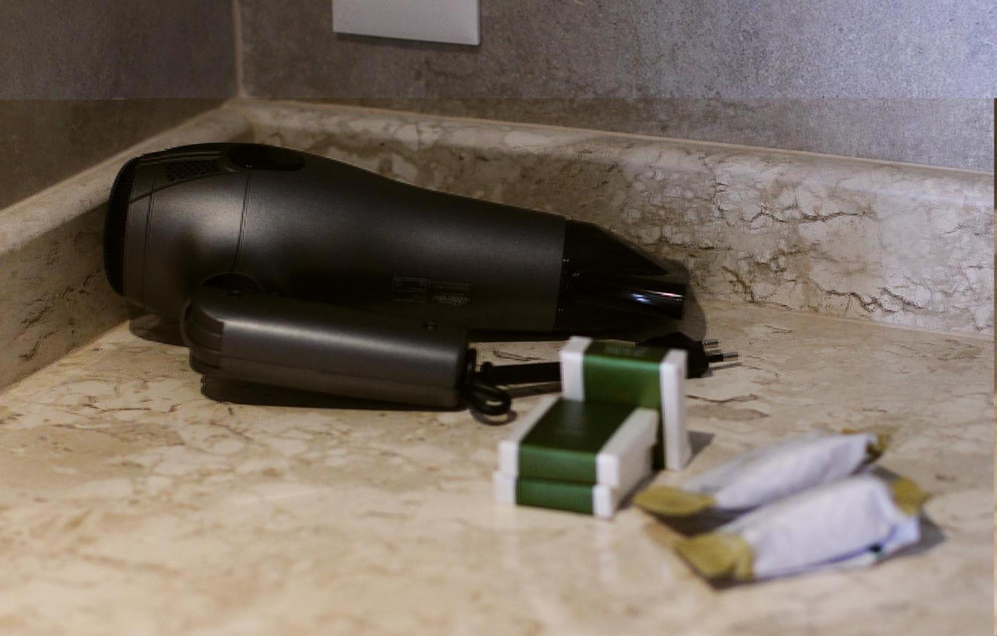 Buona Vitta Gramado Resort & Spa By Gramado Parks מראה חיצוני תמונה The photo shows a black hairdryer placed on a marble countertop. Next to the hairdryer, there are two wrapped items, likely toiletries, with green and white packaging. Additionally, there are two more items, also wrapped, which appear to be in simila