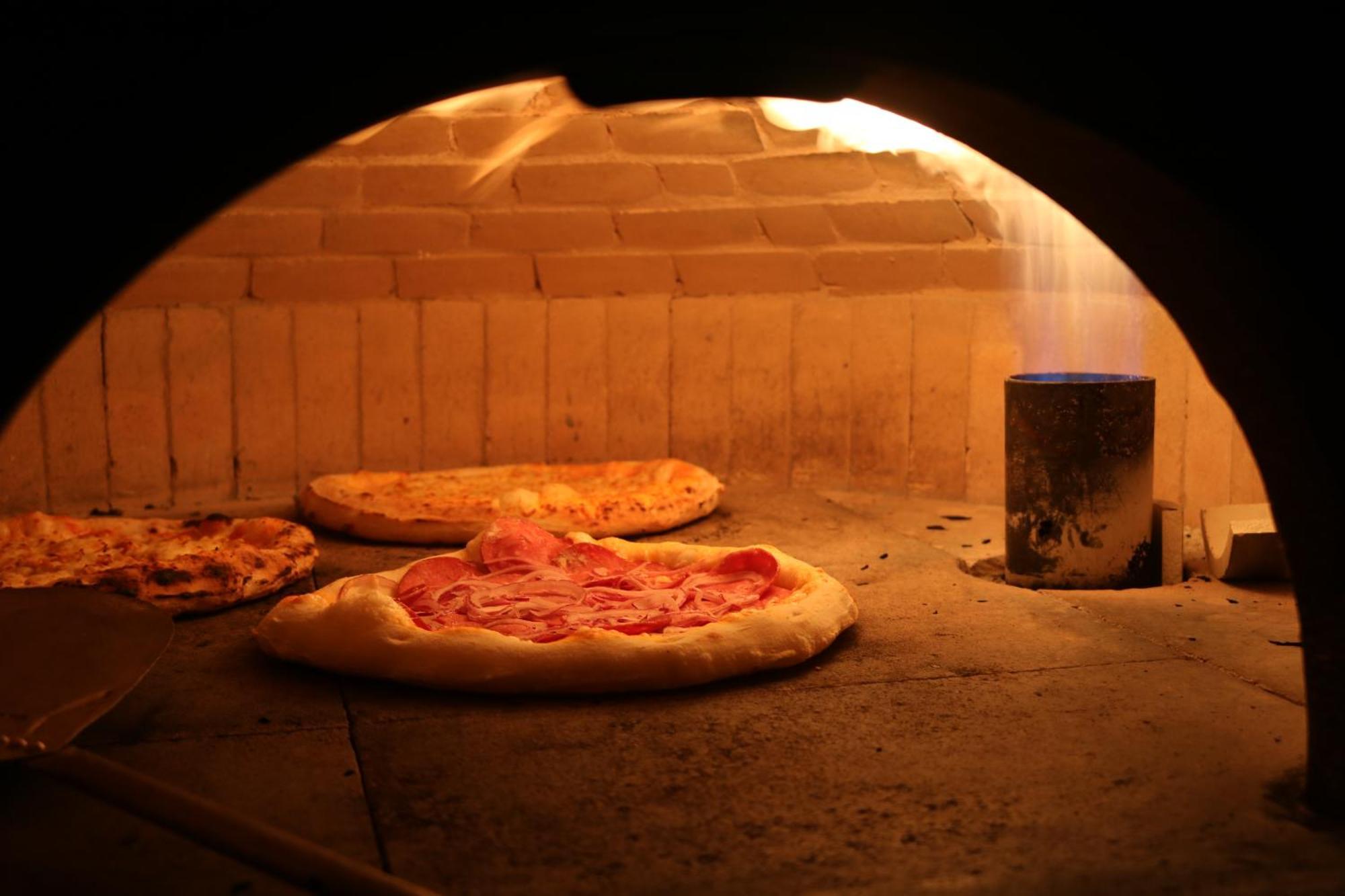 Buona Vitta Gramado Resort & Spa By Gramado Parks מראה חיצוני תמונה The photo shows a traditional pizza oven. Inside the oven, there are several pizzas placed on the stone surface. The pizzas appear to have various toppings, including what looks like cheese and possibly pepperoni. The oven has a warm, glowing ambianc