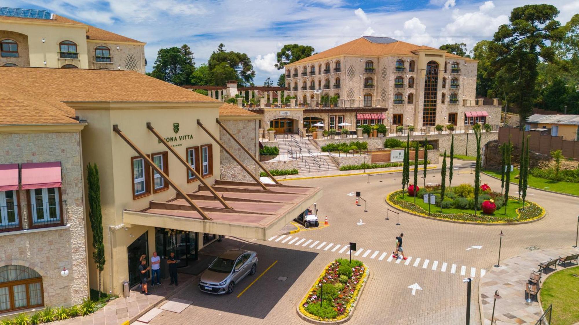 Buona Vitta Gramado Resort & Spa By Gramado Parks מראה חיצוני תמונה The photo shows a luxurious hotel or resort entrance, featuring a modern yet elegant architectural design. In the foreground, there is a covered entrance where vehicles are likely dropping off guests. The building has a stone facade and a welcoming e